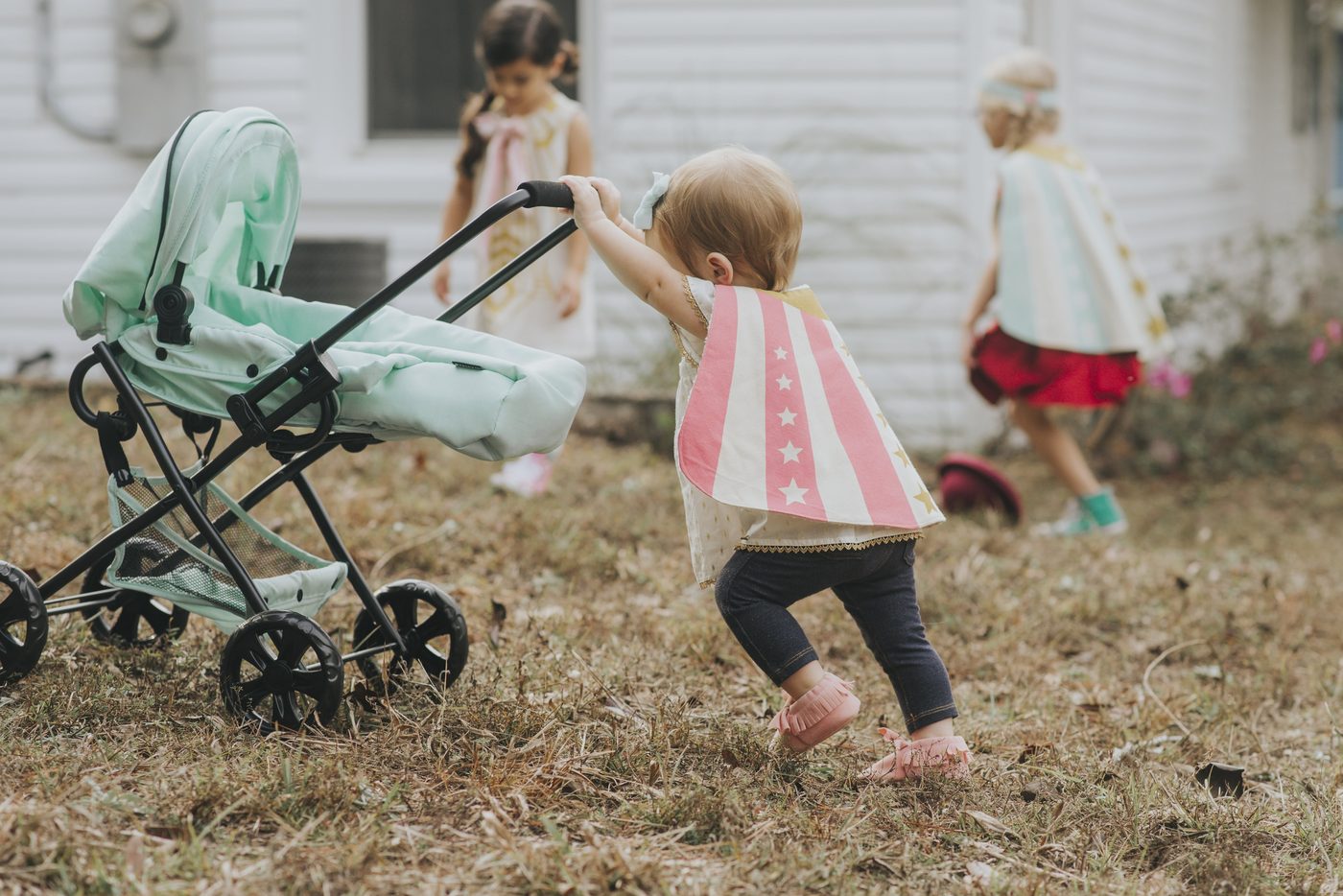 Sisters playing in a garden with a mint stroller